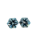 Two faceted blue gemstones on a textured surface